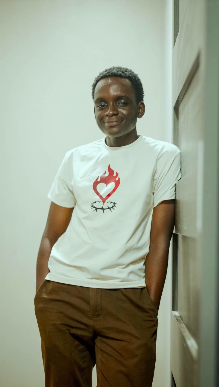 Allan Kissi Okyere smiling, leaning against a white wall